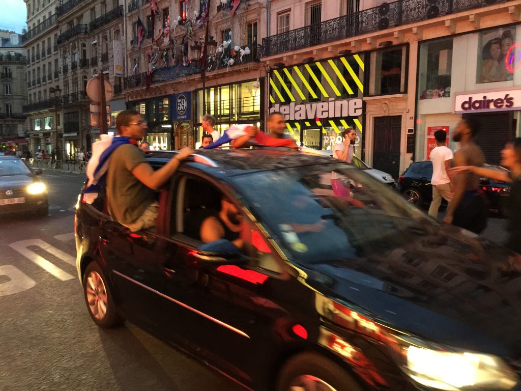 People draped in flags joyriding in the streets