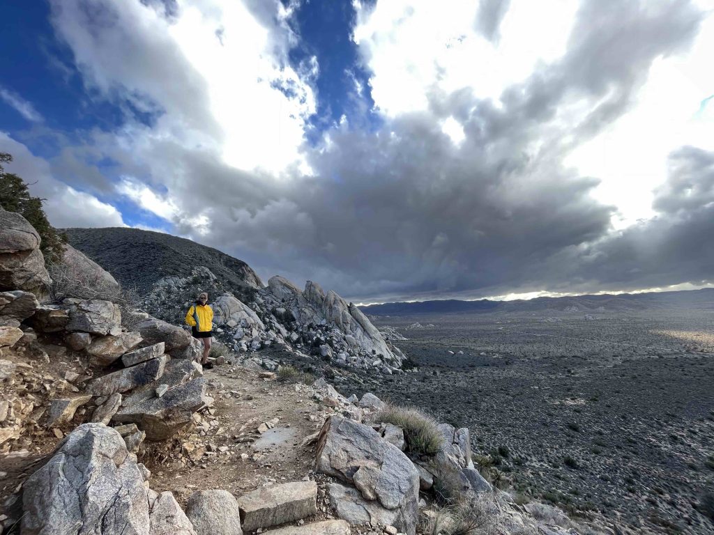 Wide-angle shot of Mary on Ryan Mountain with a stormy sky